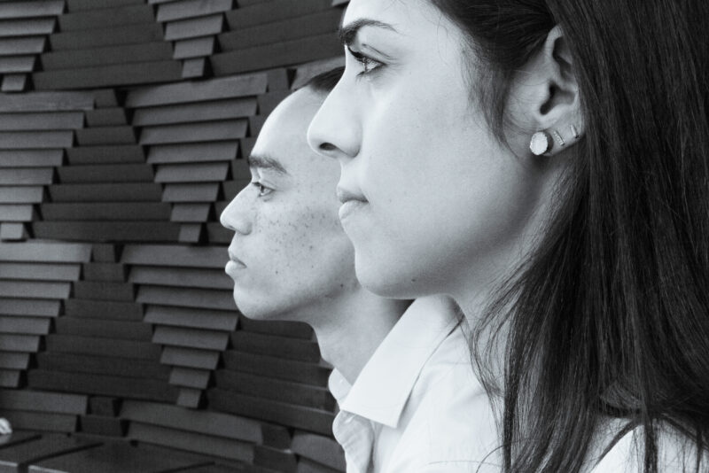 Black and white photo of a man and woman in front of a wall.