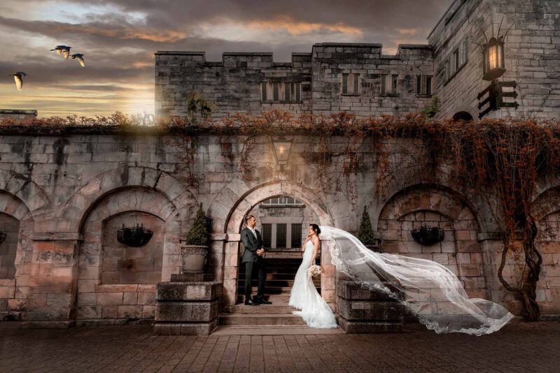 A bride and groom standing in front of a castle.