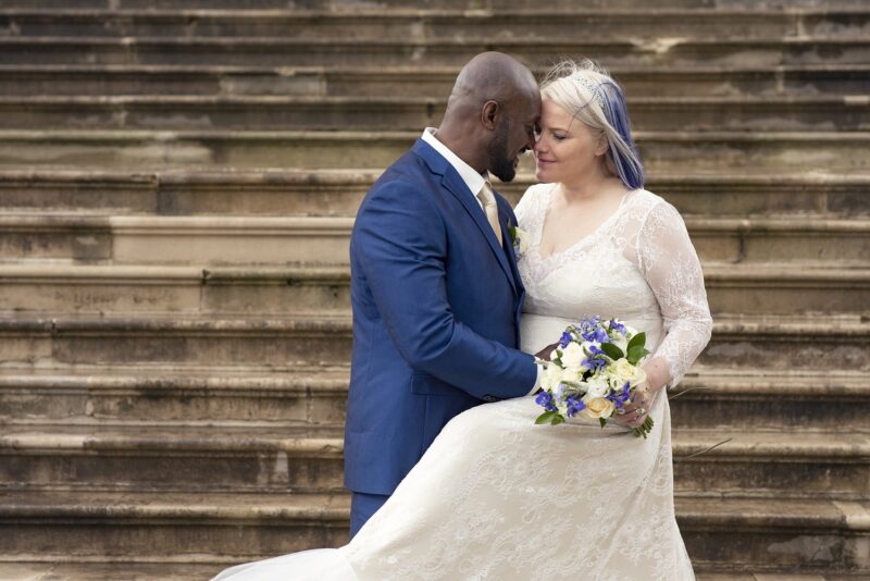 A bride and groom hugging on the steps of a building.