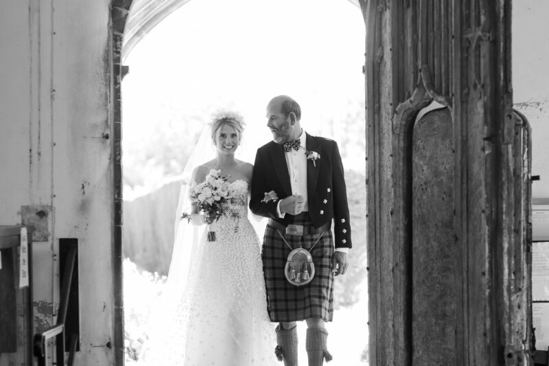 A black and white photo of a bride and groom entering a church.