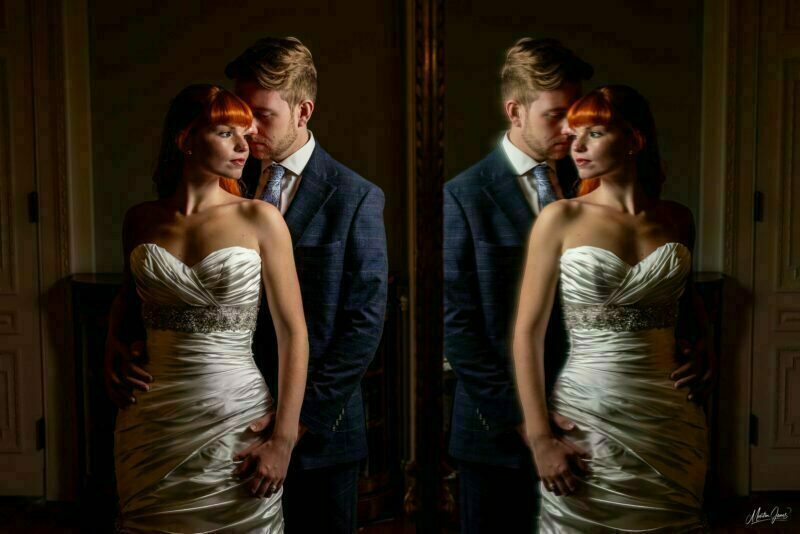 A bride and groom posing in front of a mirror.