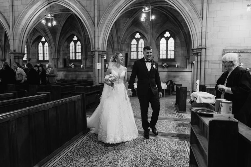 A bride and groom walking down the aisle of a church.